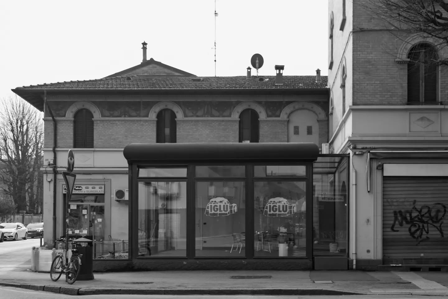 Cartoline dalla Bolognina – 2026
Le gelaterie

In un rione ci si dà appuntamento in gelateria: è dove si porta il bambino dopo i giardini e dove ci si siede fuori quando in casa fa caldo.

Per decenni se lo sono tenuto le insegne di quartiere. Iglù ha lavorato in via Barbieri dal 1990 al 2025, tutta senza glutine. Il K2 fa gelato in via Creti dal 1998 e non si è mai spostato, padre e figlio dietro il bancone. 

Nel 2012 in via Tiarini arriva Titto, e all'epoca è un evento: festa d'apertura su cinque negozi insieme, ti servi da solo e paghi a peso, in pochi mesi è franchising fino a Ibiza.

Poi si muove il centro. 

Stefino, nato in via Galliera nel 1998 e premiato con i Tre Coni del Gambero Rosso, si trasferisce qui nel 2021: la Bolognina è la sua unica sede. 

Al posto di Iglù apre la Cremeria d'Azeglio, che del centro porta ancora il nome, e all'incrocio con Fioravanti si fa la fila.

Il gelato si prendeva sotto casa. Adesso in Bolognina ci si viene apposta.